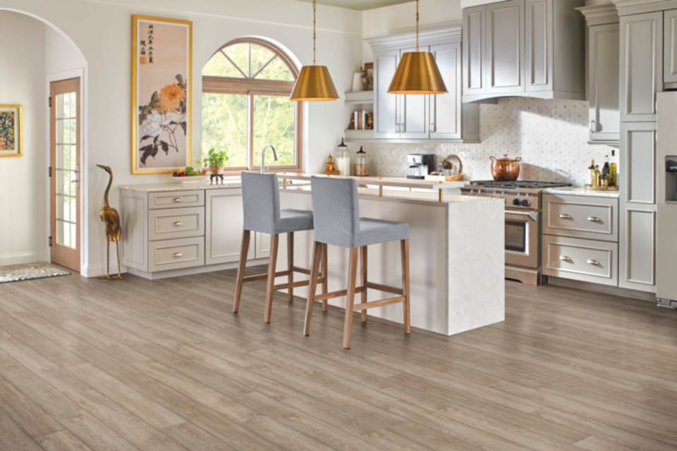 cream kitchen cabinets in kitchen with stone kitchen island and grey chairs.